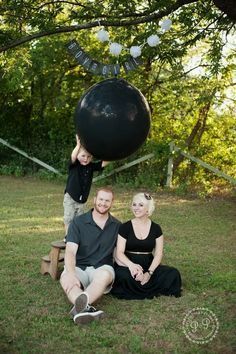 a man and woman sitting on the ground with a large black object in front of them