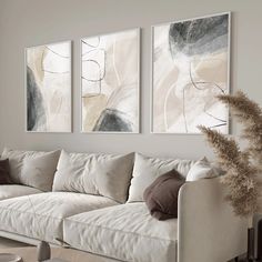 a living room with white couches and paintings on the wall