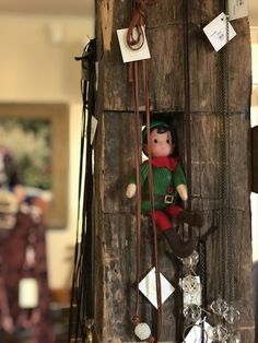 an elf doll hanging from the side of a wooden pole with other items around it