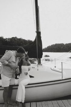 a man and woman kissing on the deck of a sailboat in black and white