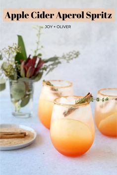 four glasses filled with drinks sitting on top of a table next to a plate and flowers