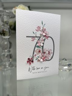 a white card with pink flowers and the letter d on it is sitting on a table