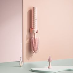 two hairbrushes and a comb on a pink wall next to a white sculpture