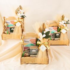 two wooden baskets filled with assorted items on top of a white cloth covered bed