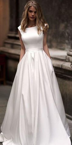 a woman in a white wedding dress is walking down the street with her hand on her hip