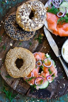 an assortment of bagels and salmon on a wooden board