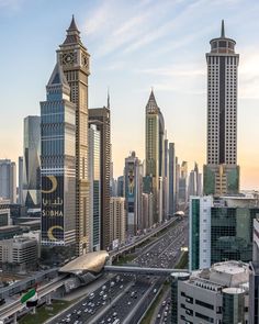 an aerial view of a city with skyscrapers and cars driving on the road in front of them