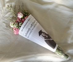 a bouquet of flowers laying on top of a white sheet with a book in the middle