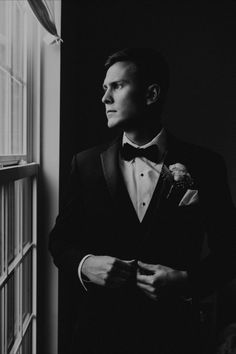 a man in a tuxedo looking out the window