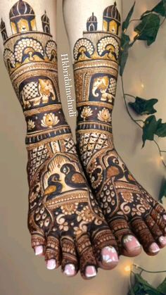 the legs and feet of a woman with henna tattoos on their hands, decorated with gold