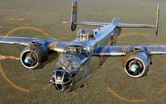 an old airplane is flying in the sky over some dirt and grass with circles around it