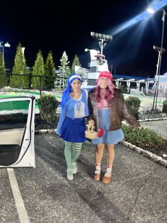 two women are walking in the parking lot at night with their umbrellas up and one is holding a basket