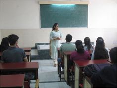 a woman standing in front of a classroom full of students