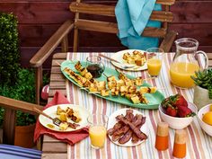 a table topped with plates of food next to glasses of orange juice and strawberries