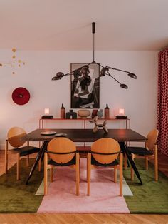 a dining room table with four chairs and a rug on the floor in front of it