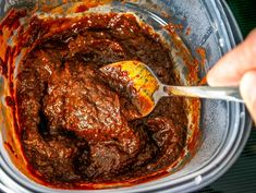 a person is mixing some food in a blender with a ladle and spoon