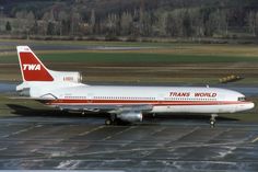 a large passenger jet sitting on top of an airport tarmac with trees in the background