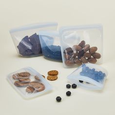 three plastic containers filled with nuts and other food items next to each other on a white surface