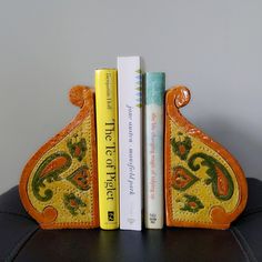 two books are sitting next to each other on a leather chair with an orange and yellow bookend