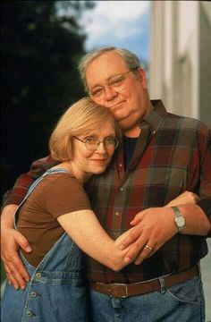 an older man and woman hugging each other