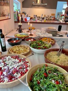 a table topped with lots of bowls filled with food next to a bottle of wine