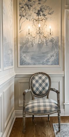 a chair sitting in front of a wall with a chandelier hanging from it