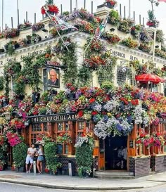 two people standing in front of a building with flowers on it