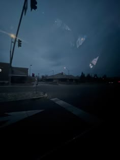 a traffic light sitting on the side of a road next to a street sign at night