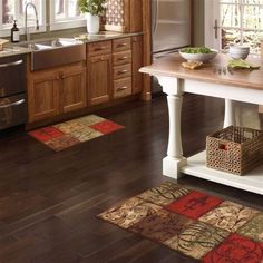 a kitchen with wood flooring and wooden cabinets is pictured in this image, there are two rugs on the counter