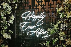 there is a neon sign that says happily ever after it's been decorated with flowers