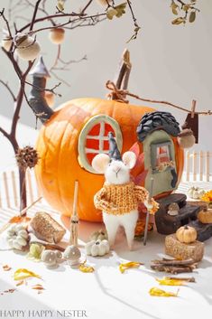 a mouse figurine sitting in front of a pumpkin with other decorations around it