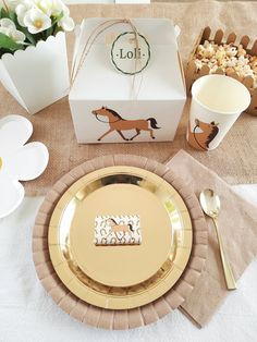 a table set with gold plates, napkins, and boxes for food to be eaten