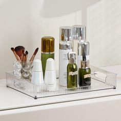 several bottles and containers are sitting on a counter top with makeup brushes, eyeliners, and other items