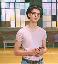 a young man wearing glasses holding a cell phone