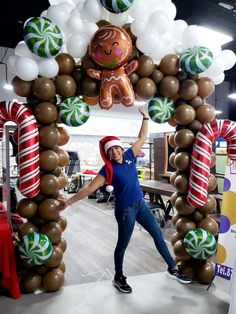 a woman is posing in front of an arch made out of balloons and candy canes