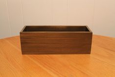 a small wooden box sitting on top of a wooden table next to a white wall