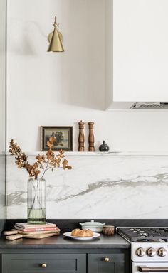 a kitchen with marble counter tops and black cabinets, an oven and range hood in the background