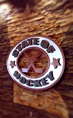 the state of hockey emblem is mounted on a wooden paneled wall with stars around it