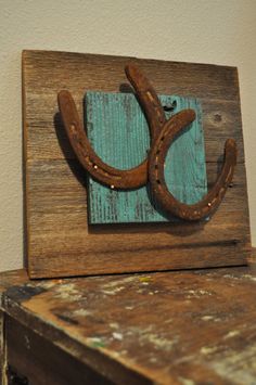 a wooden sign with horseshoes hanging from it's sides on a shelf next to a wall