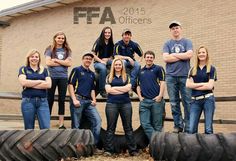 a group of people standing next to each other in front of a building with tires