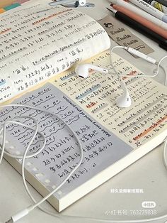 an open book sitting on top of a desk next to headphones