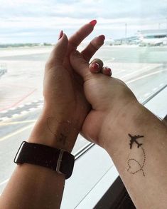 two hands holding each other with an airplane in the sky behind them and a plane on the ground