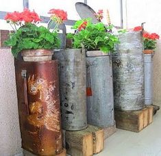 four metal containers with flowers in them sitting on the side of a building next to each other