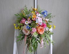 a bouquet of flowers sitting on top of a white stepladder in front of a wall