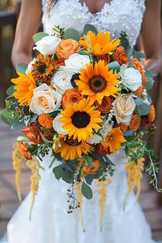 a bride holding a wedding bouquet with sunflowers and roses on it's side