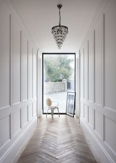 an empty hallway with white walls and wood flooring