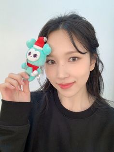 a woman holding up a stuffed animal toy to her eye and smiling at the camera