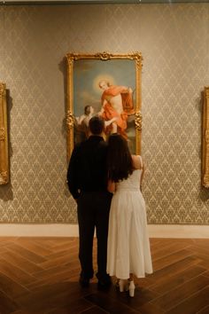 a man and woman standing in front of a painting