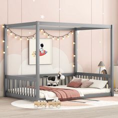 a child's bedroom with pink walls and white furniture, including a gray bed frame