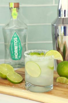 a margarita with limes on the rim and a shaker next to it